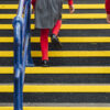 A low angle legs only view of a boy and a girl walking upstairs in a public transport station with yellow QuartzGrip Anti-Slip stair nosing on each step